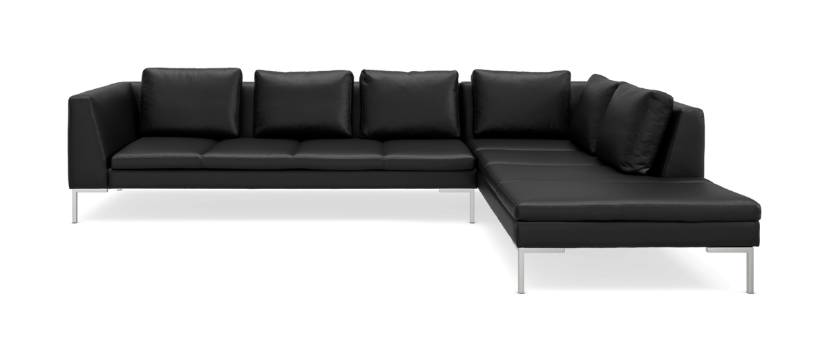 Svart L‑formad hörnsoffa med slanka metallben och lösa ryggkuddar i modern stil.