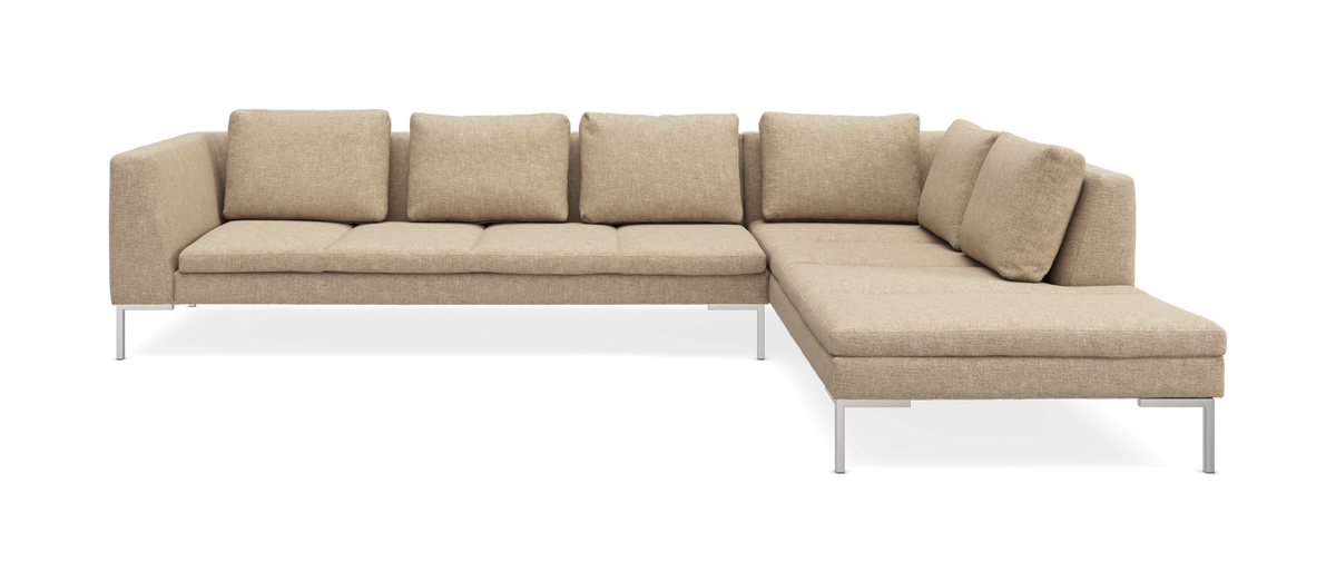 Beige L-formad modulsoffa med metallben och lösa ryggkuddar.