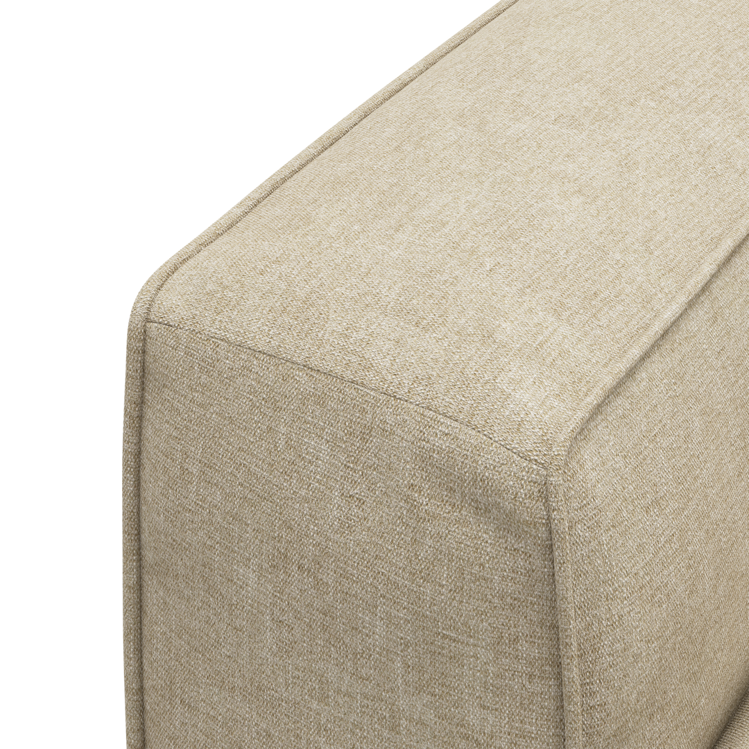 Närbild av beige textilklädd soffa/puff-modul med synliga sömmar.
