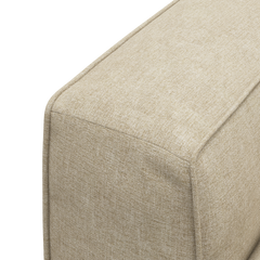 Närbild av beige textilklädd soffa/puff-modul med synliga sömmar.