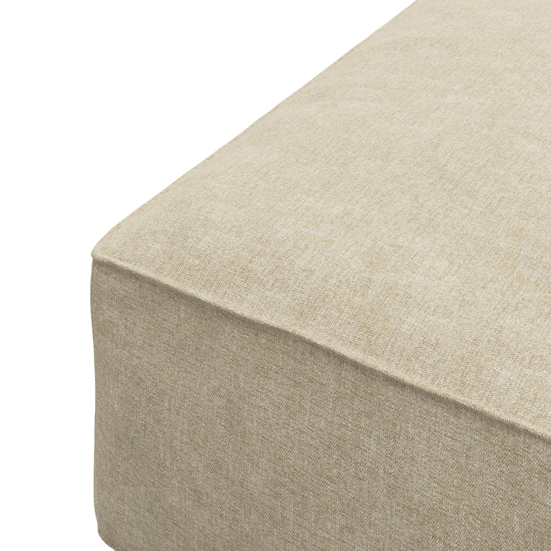 Närbild av hörnet på en beige tygklädd sittpuff/ottoman med rena sömmar.