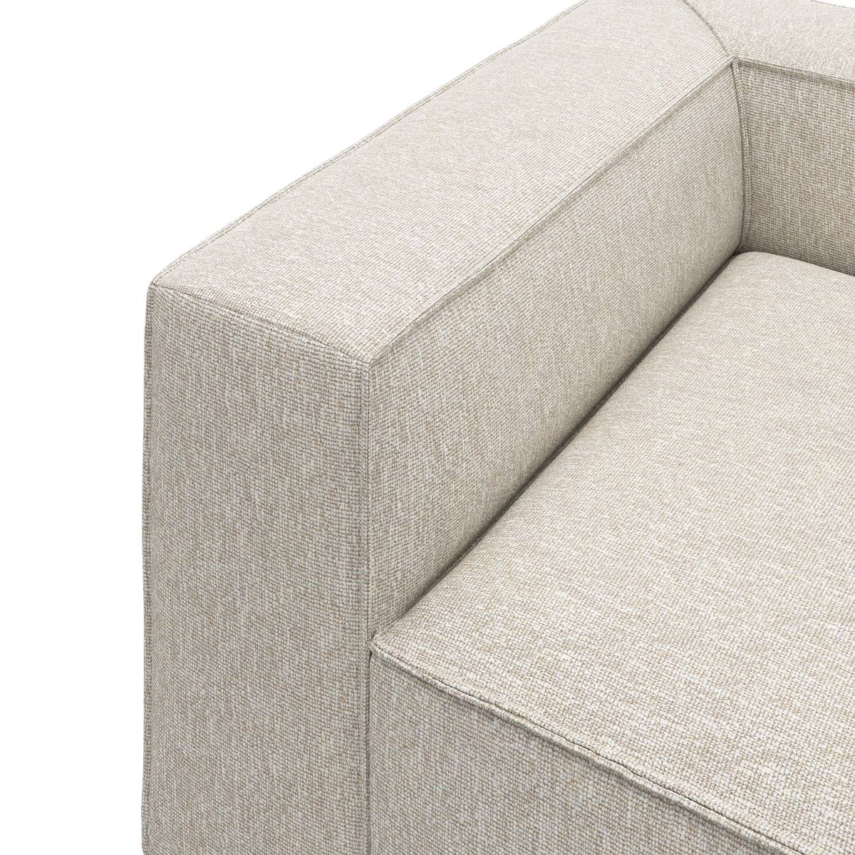 Närbild av beige textilsoffa med kraftigt armstöd och sits mot vit bakgrund.