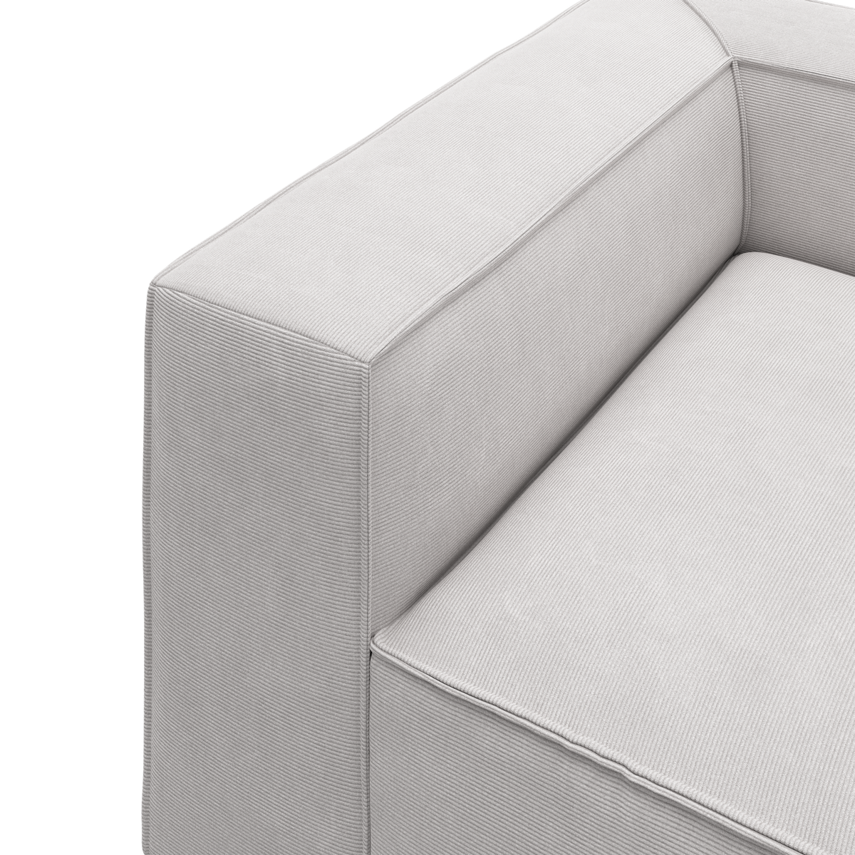 Ljusgrå soffa i närbild med bredt armstöd och sits i finribbat tyg, modern minimalistisk design mot vit studiobakgrund.