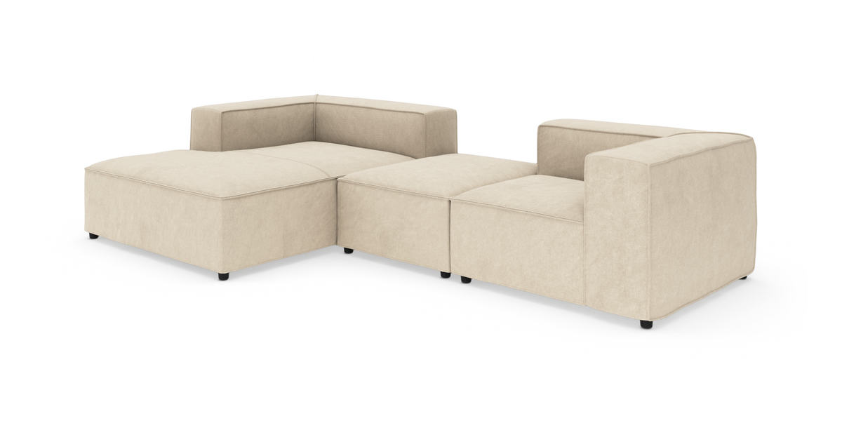 Beige modulsoffa i L‑form med bred schäslong och låga svarta ben, frilagd på vit bakgrund.