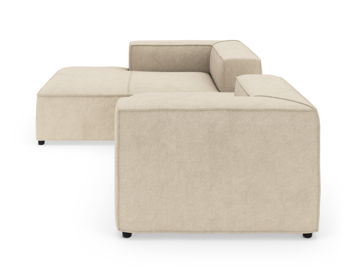 Beige modulsoffa i hörnutförande sedd bakifrån på vit studiobakgrund.
