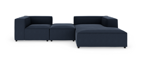 Modulsoffa i mörkblått tyg, L‑form med bred schäslong och låga armstöd, produktbild mot vit bakgrund.