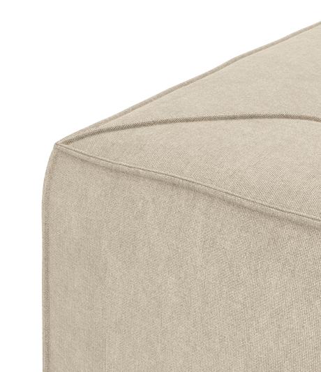 Beige tygpuff, närbild av hörn med synliga diagonala sömmar.
