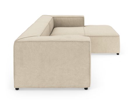 Beige modulsoffa i L-form med breda armstöd, visad från sidan på vit bakgrund.