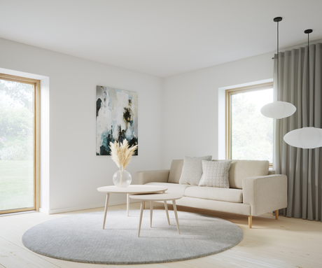 Ljus skandinavisk vardagsrumsinteriör med beige soffa, runda soffbord, grå rund matta, pampas i glasvas, abstrakt tavla och rispapperspendlar vid stora fönster.