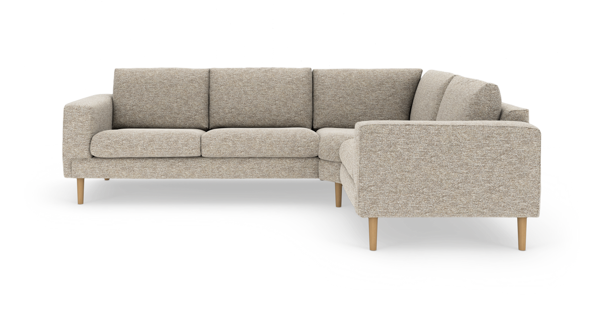 Beige L-soffa i tyg med ljusa träben, frilagd på vit bakgrund.