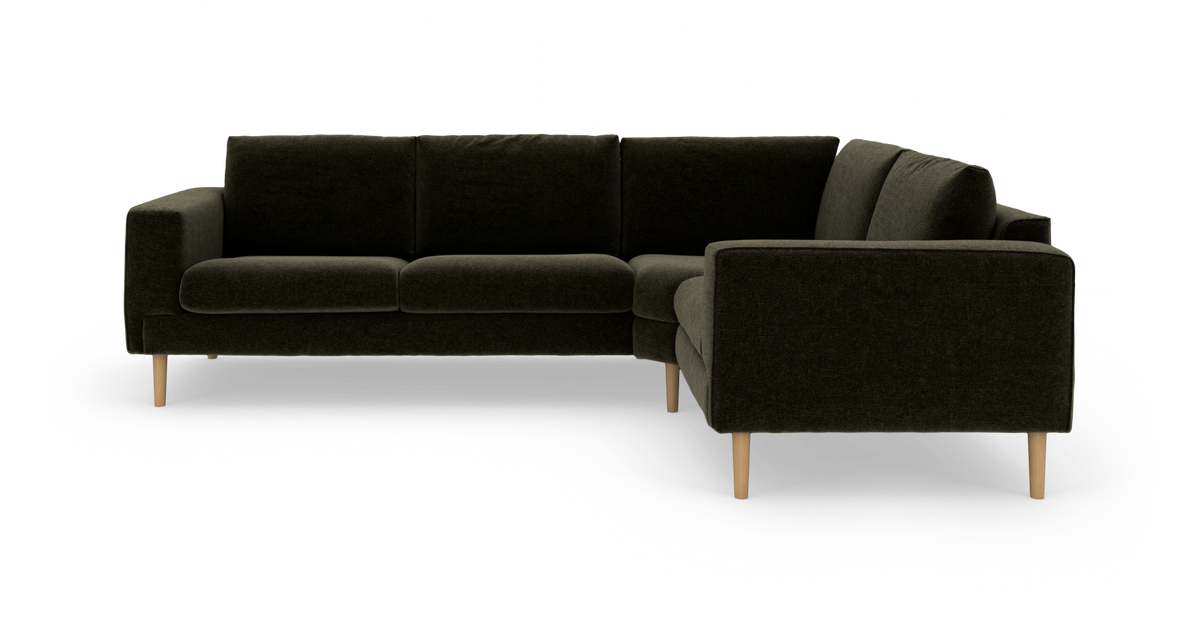 Mörkgrön L-formad hörnsoffa med träben, frilagd på vit bakgrund.