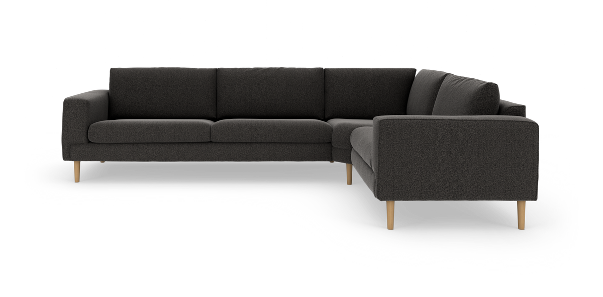 Mörkgrå L-formad hörnsoffa med ljusa träben, minimalistisk design i studiomiljö.