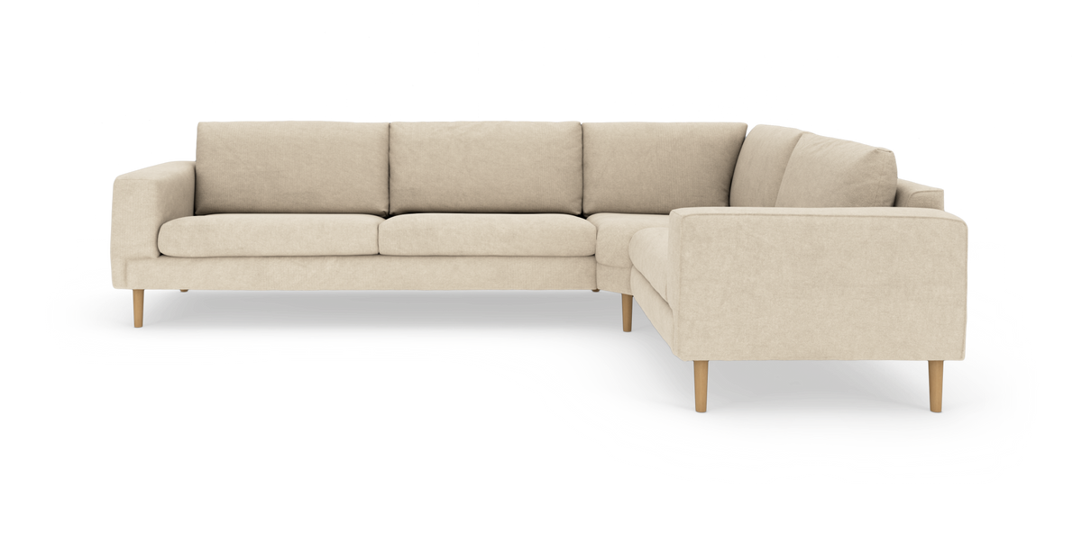 Beige L‑formad soffa med tygklädsel och träben, frilagd mot vit bakgrund.