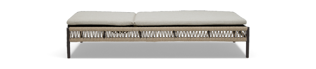 Lång bänk med ljusbeige dyna och flätad repbas på mörka ben, frilagd mot vit bakgrund.