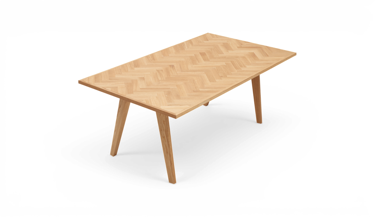 Rektangulärt matbord i ek med fiskbensmönstrad bordsskiva och vinklade ben, fotat snett framifrån.