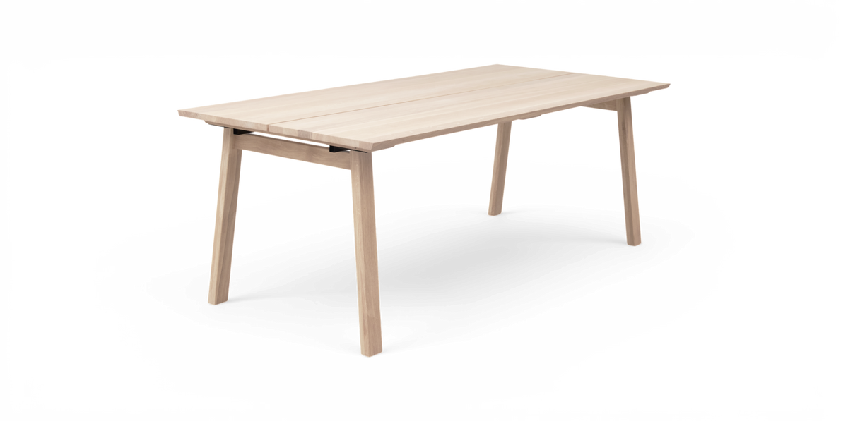 Ljus ekfärgat rektangulärt matbord i minimalistisk design frilagt mot vit bakgrund, sned framvinkel.