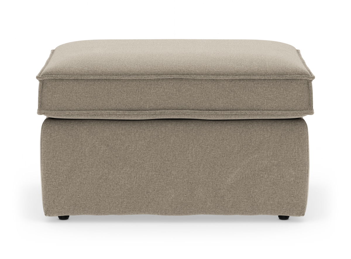 Beige tygklädd fotpall/puff med mjuk boxkudde och kjolad bas, frilagd mot vit bakgrund.