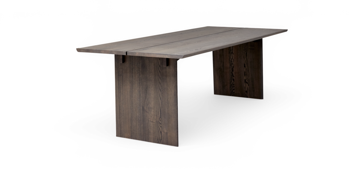 Mörkbetsat matbord i trä med plankad bordsskiva och två panelben i minimalistisk design, frilagd på vit bakgrund.