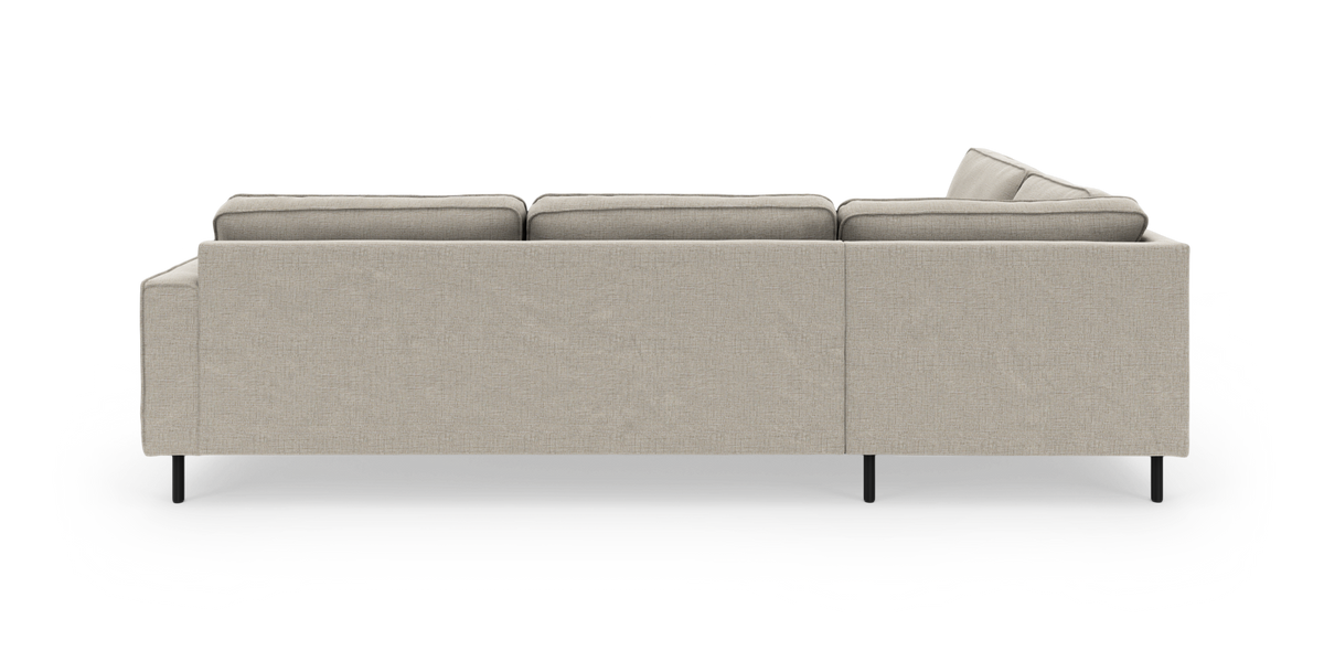 Beige modulsoffa med chäslong, sedd bakifrån på vit bakgrund med svarta metallben.