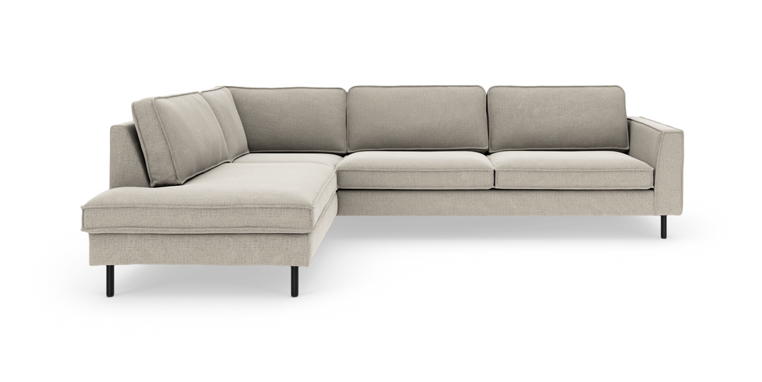 L-formad modulsoffa med vänster schäslong i ljus beige tyg och smala svarta metallben, frilagd på vit bakgrund.