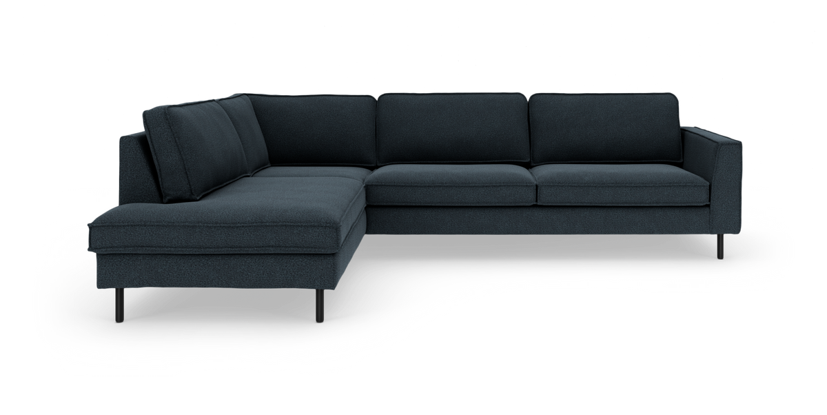 Mörkblå L‑formad hörnsoffa med schäslong till vänster, smala svarta ben och modern, ren design frilagd på vit bakgrund.