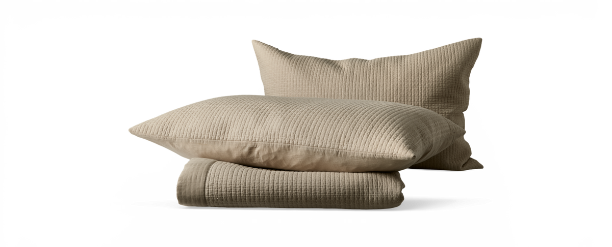 Beige quiltade kuddar med matchande vikt överkast.