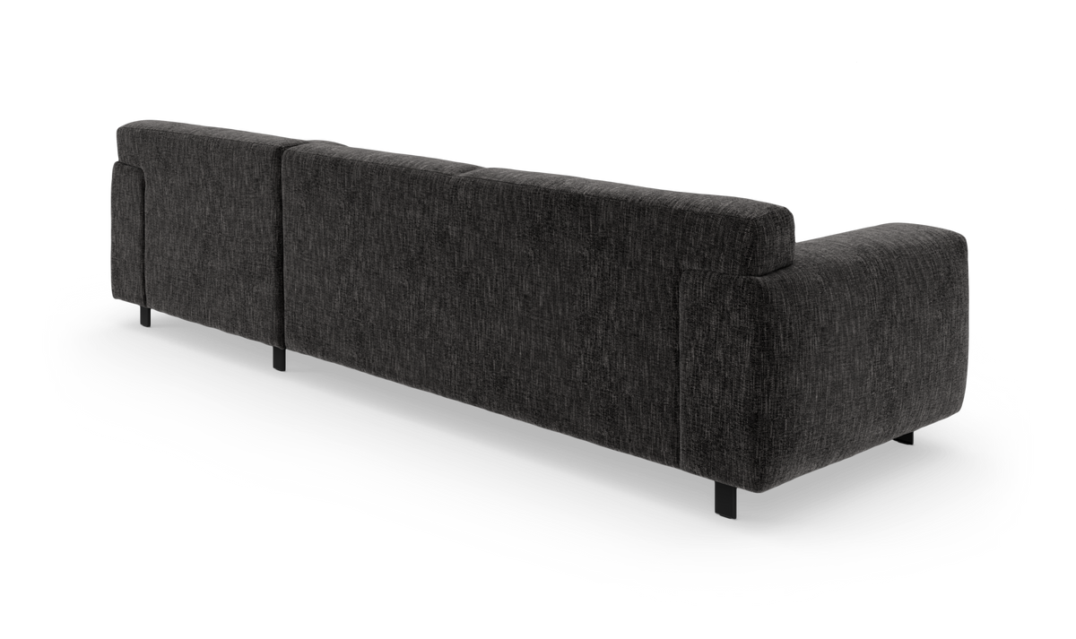 Mörkgrå, modern soffa i tyg sedd bakifrån i en studiomiljö, lätt bakåtvinklad med svarta ben.