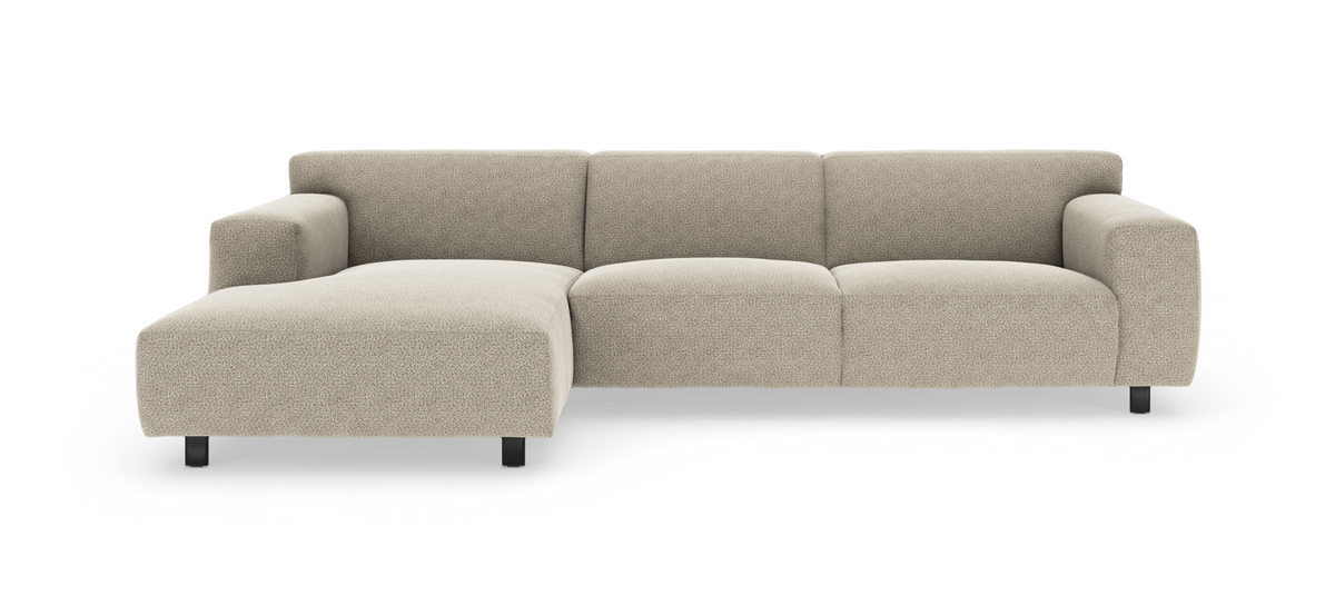Beige modulsoffa med vänstersvängd divan, låg rygg och svarta ben, frilagd mot vit bakgrund.
