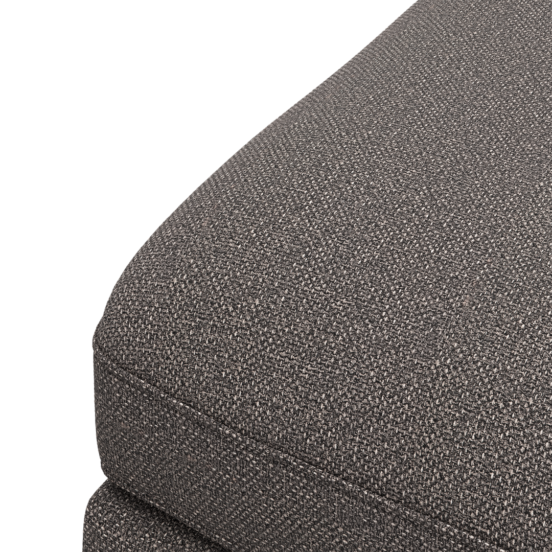 Närbild av mörkgrå, texturerad tygklädsel på hörnet av en soffas sätesdyna.