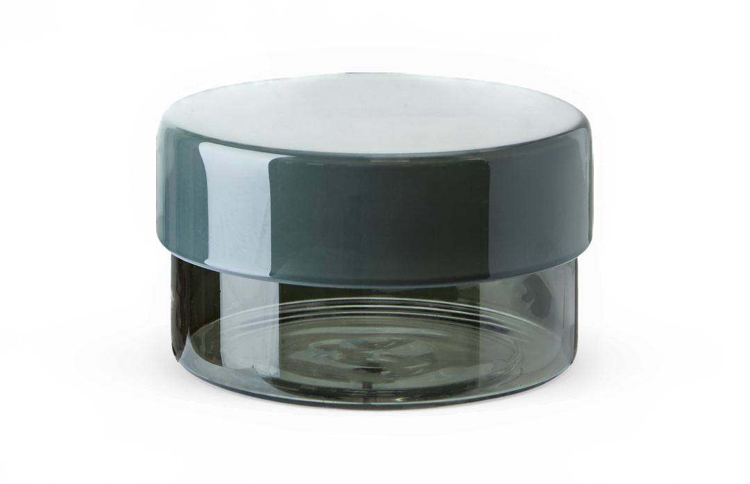 Liten rund glasburk med röktonad transparent nederdel och blankt mörkgrågrönt lock.