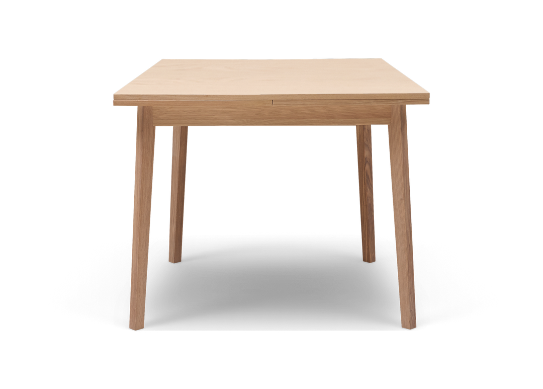 Framifrånvy av ett minimalistiskt matbord i ljus ek mot vit bakgrund.
