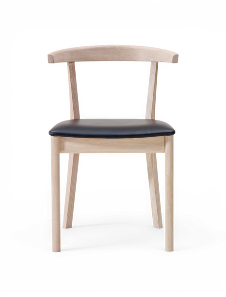 Stol i ljust trä med svart sits, frontvy mot frilagd bakgrund.