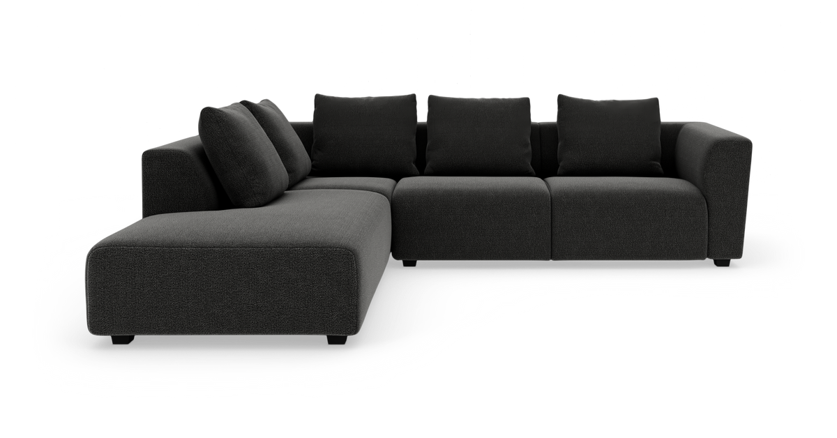 Mörkgrå L‑soffa med vänster divan och fyra ryggkuddar i modern design, fristående mot vit bakgrund.