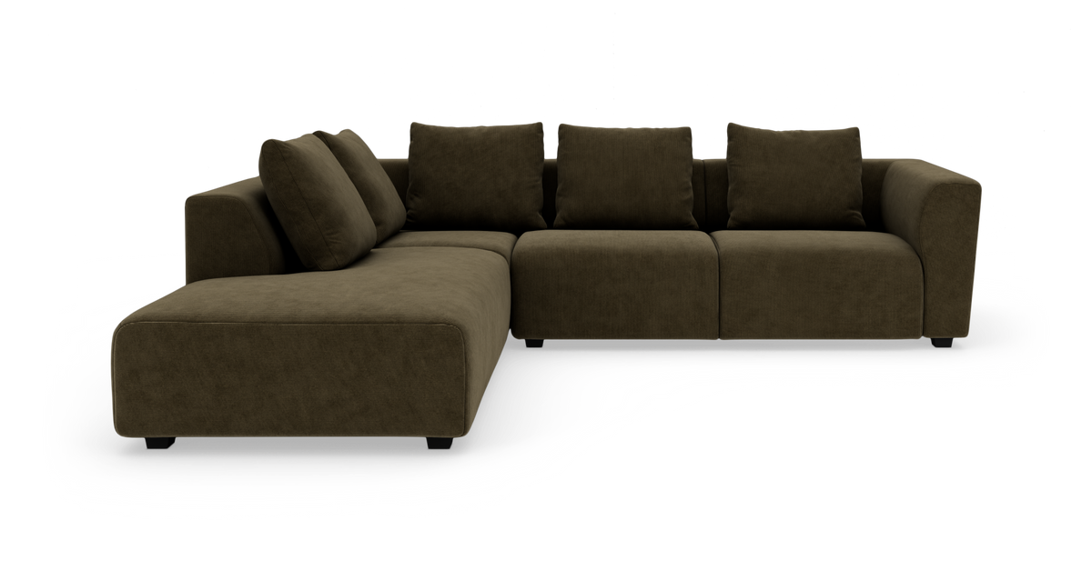 Mörk olivgrön L-formad modulsoffa med divan till vänster, breda armstöd och lösa ryggkuddar på vit bakgrund.