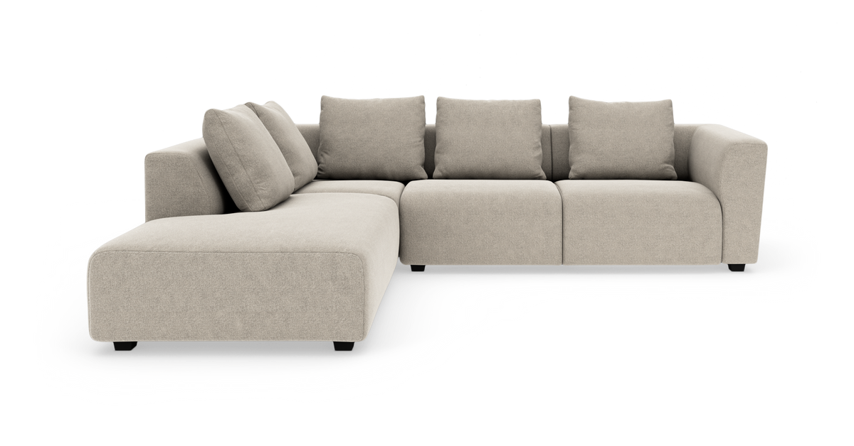 Beige modulsoffa i L-form med bred schäslong och fyra ryggkuddar.