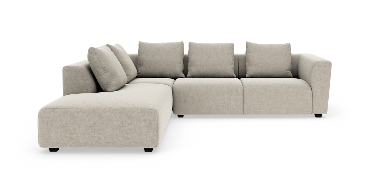 Beige modulsoffa i L‑form med fyra ryggkuddar och bred schäslong.
