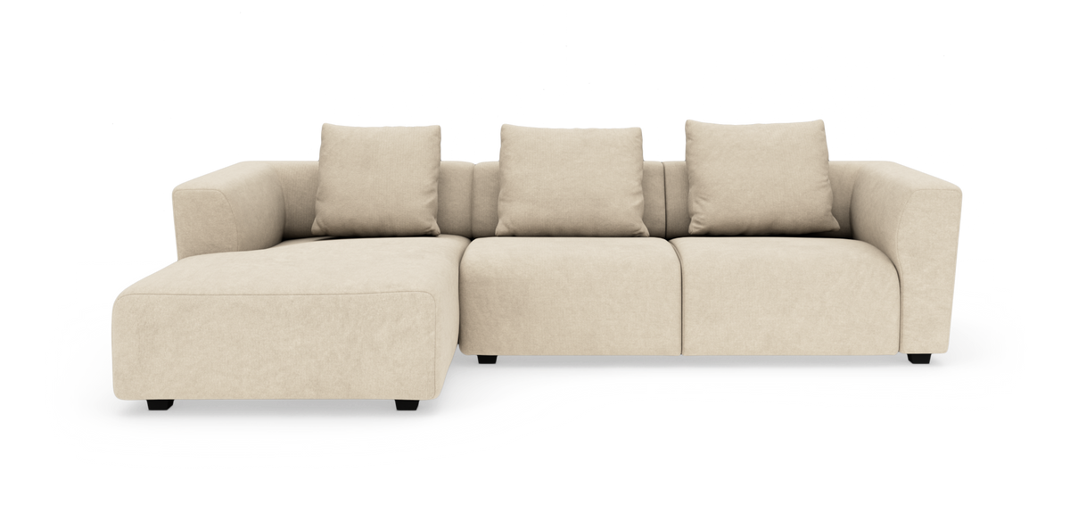 Beige modulsoffa med schäslong till vänster och fyra ryggkuddar, frilagd på vit bakgrund.