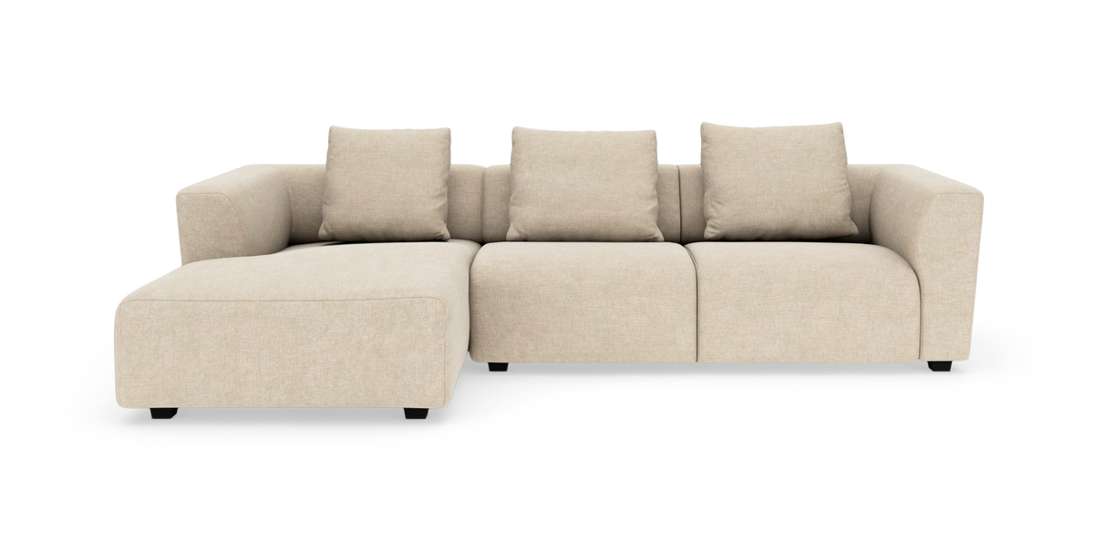Beige modulsoffa med schäslong till vänster och tre ryggkuddar, frilagd på vit bakgrund.