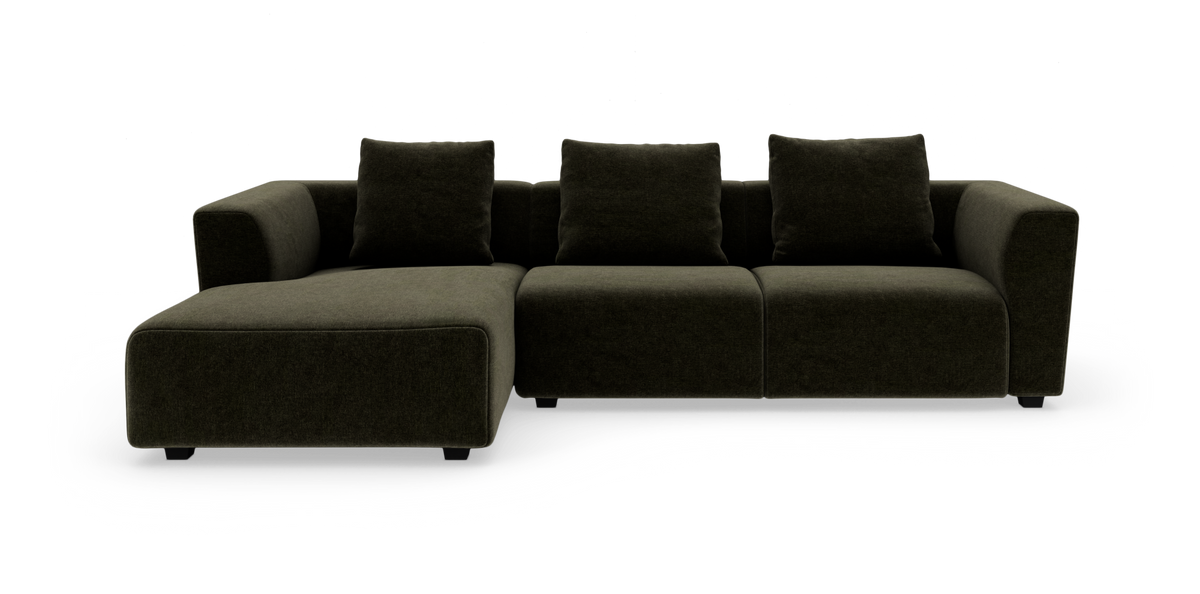 Modulsoffa i mörk olivgrön textil med vänsterställd schäslong och tre lösa ryggkuddar, fristående på vit bakgrund.