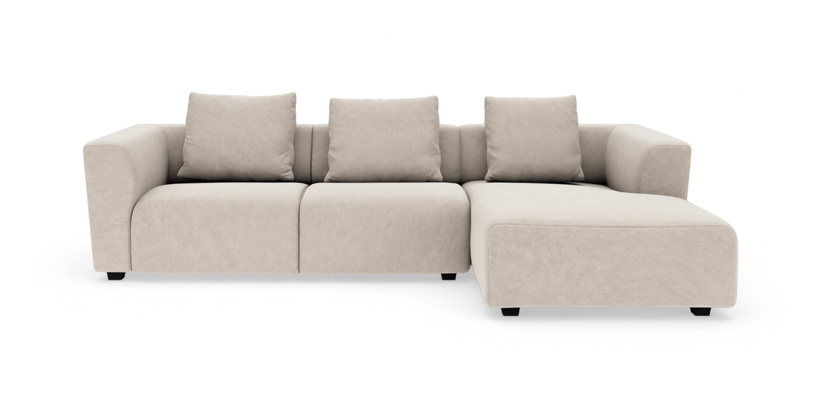 Beige modulsoffa i L-form med schäslong till höger, sedd rakt fram mot vit bakgrund.