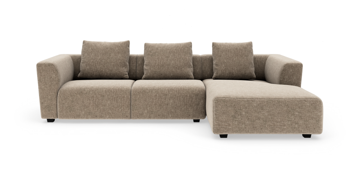 Beige modulsoffa med högersidig chaiselong, tre sittplatser och fyra ryggkuddar, frontvy mot vit bakgrund.