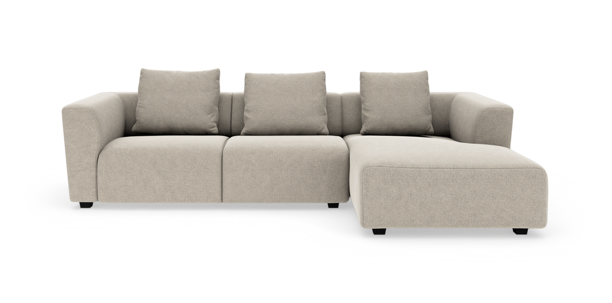 Beige modulsoffa med högerställd schäslong, tre sittplatser och fyra ryggkuddar, frilagd mot vit bakgrund.