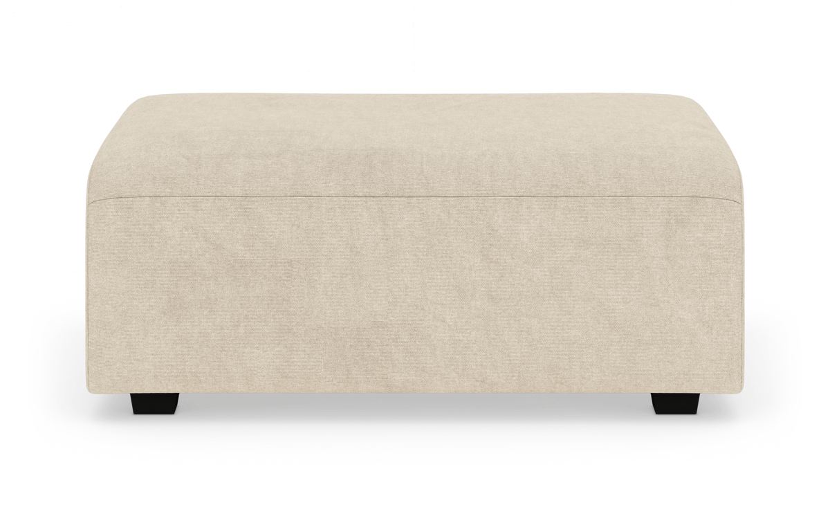 Beige rektangulär puff/fotpall i tyg, frontvy mot vit bakgrund.