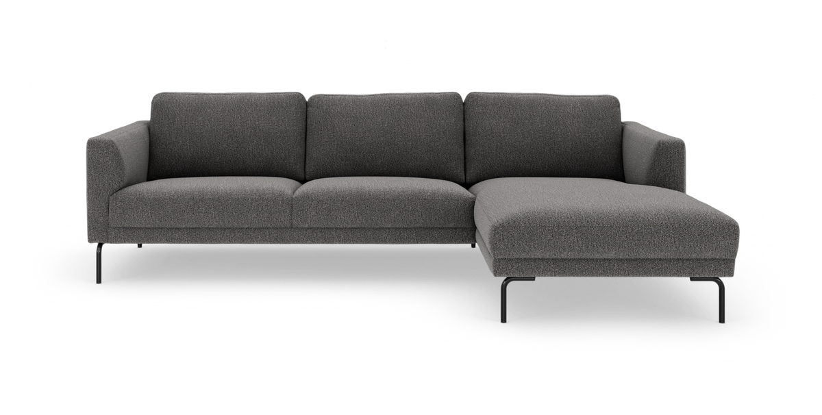 Mörkgrå 3-sits soffa med schäslong till höger och slanka svarta metallben, frilagd mot vit bakgrund.