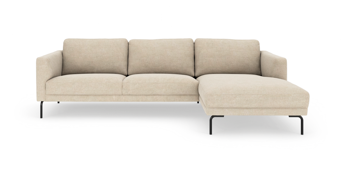 Beige hörnsoffa med höger schäslong på smala svarta metallben, modern och minimalistisk, sedd rakt framifrån mot vit studiobakgrund.
