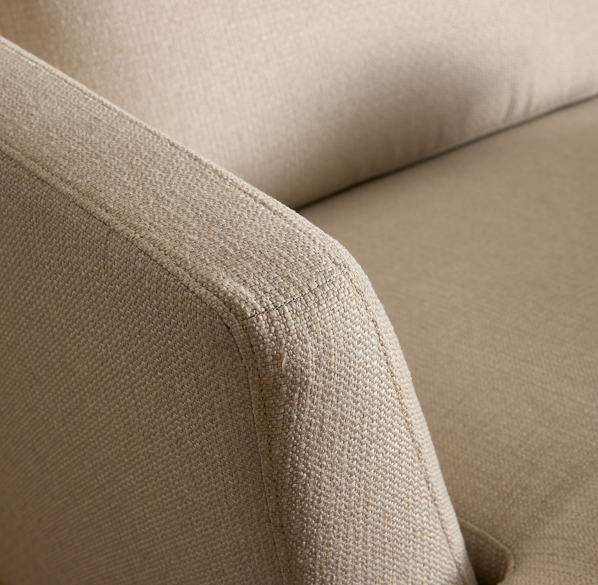 Närbild av beige soffarmstöd i texturerat tyg.