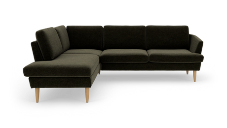 Mörkgrön L‑soffa med vänstervänd schäslong och ljusa treben i modern skandinavisk design.