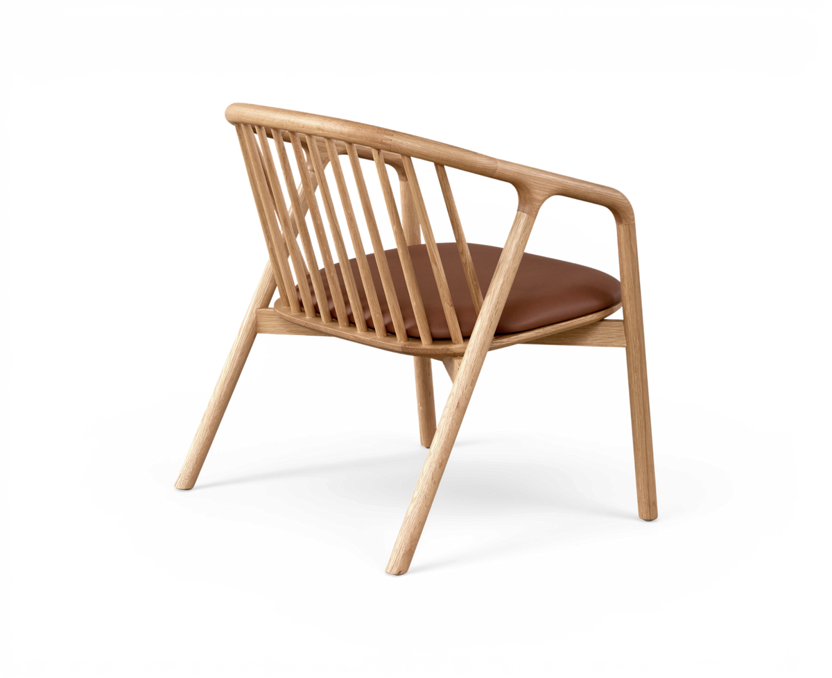 Bakåtvinklad vy av en skandinavisk loungestol i trä med spjälrygg och brun lädersits på vit bakgrund.