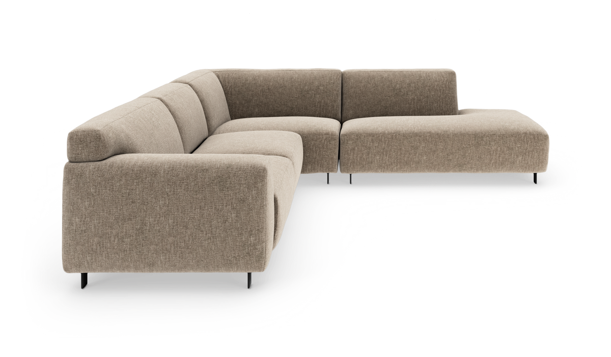 Beige modulsoffa i L‑form med låg rygg och smala svarta ben, frilagd på vit bakgrund.