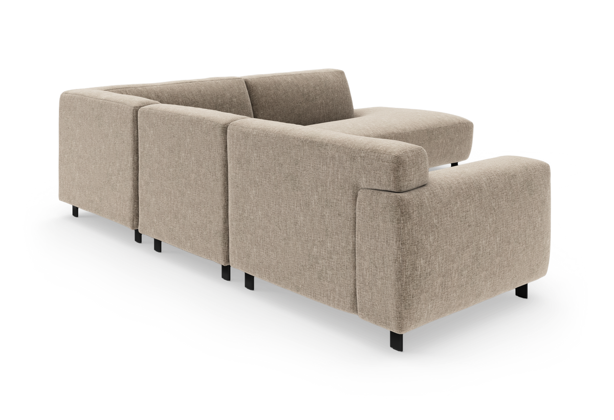 Beige modulsoffa i hörnsektion, sedd snett bakifrån på vit bakgrund.